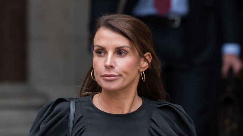 Coleen Rooney in a black dress looking serious