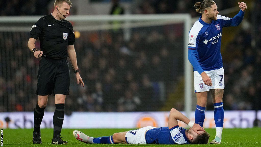 Ipswich's George Hirst on the ground with his hands on his face after suffering a hamstring injury