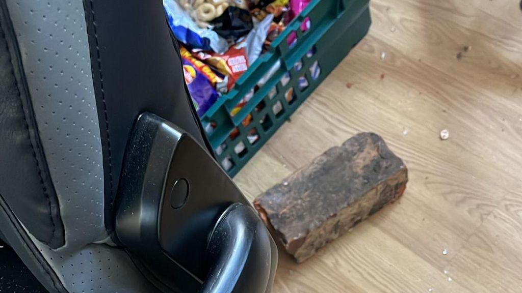 A brick on the floor next to a food bank box and a chair in the office of the charity