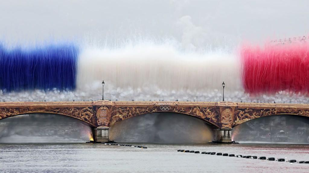 Smoke resembling the flag of Team France is shown over Pont d’Austerlitz during the opening ceremony of the Olympic Games