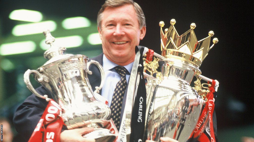 Sir Alex Ferguson holding trophies