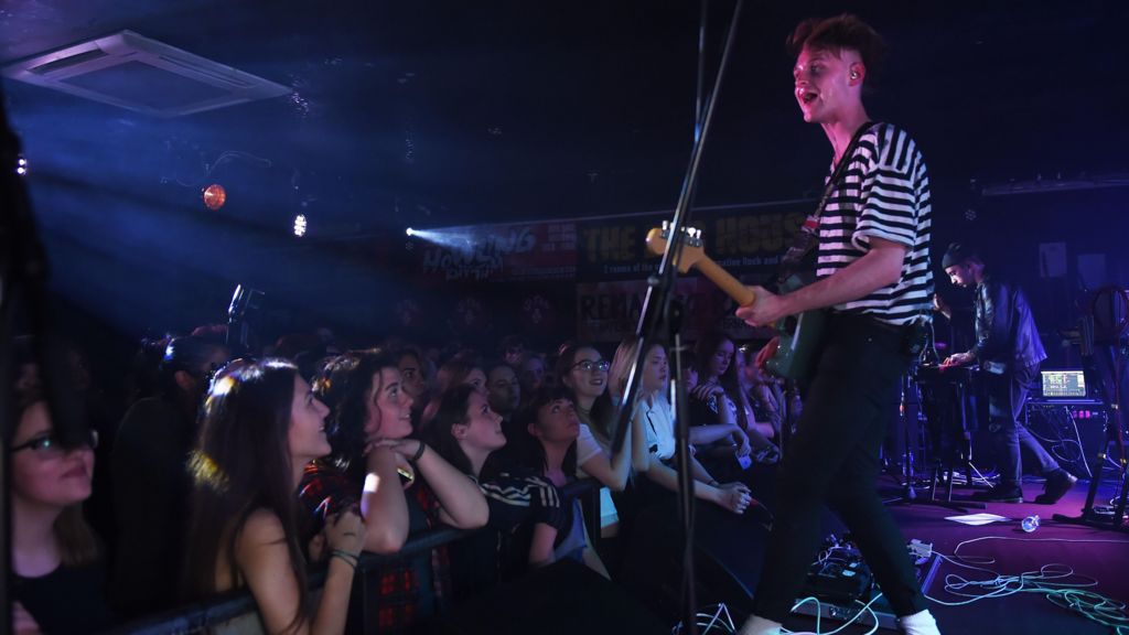 Sam Battle on stage playing the guitar in front of fans