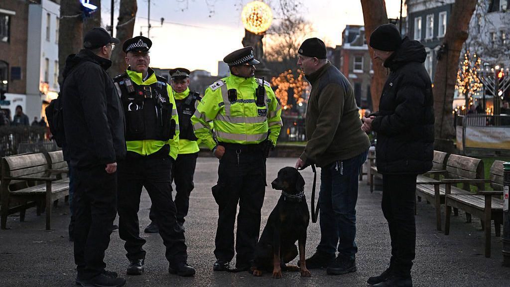 Police officers seen with a dog, attend the Menorah Lighting, celebrating the Festival of Chanukah in Islington, London