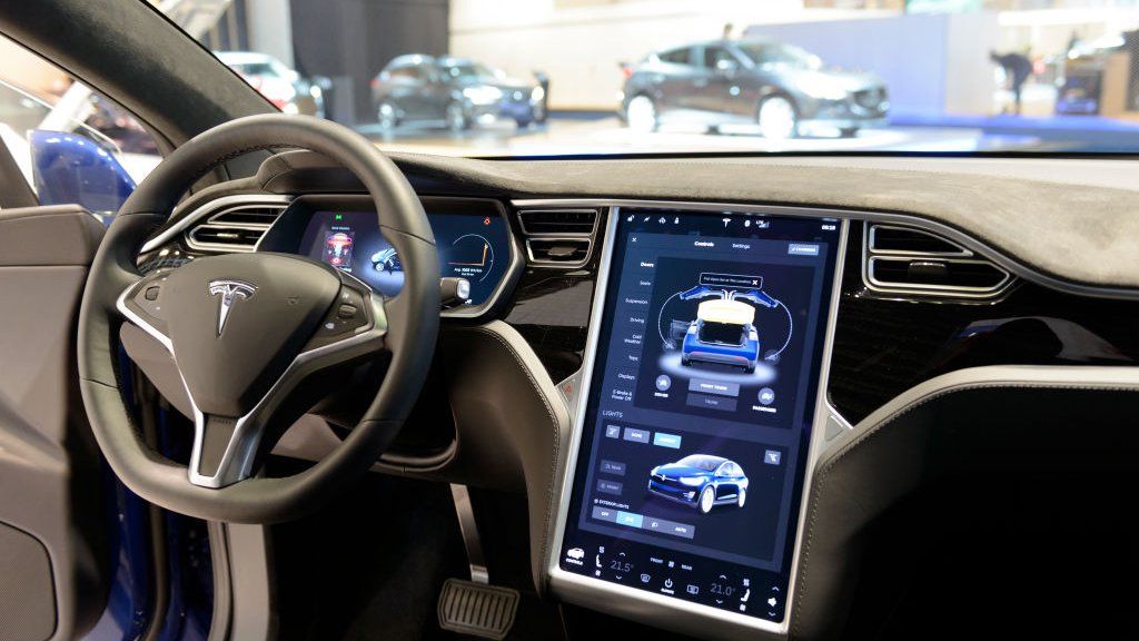 The interior on a Tesla Model S full electric luxury car with a large touch screen and dashboard screen.