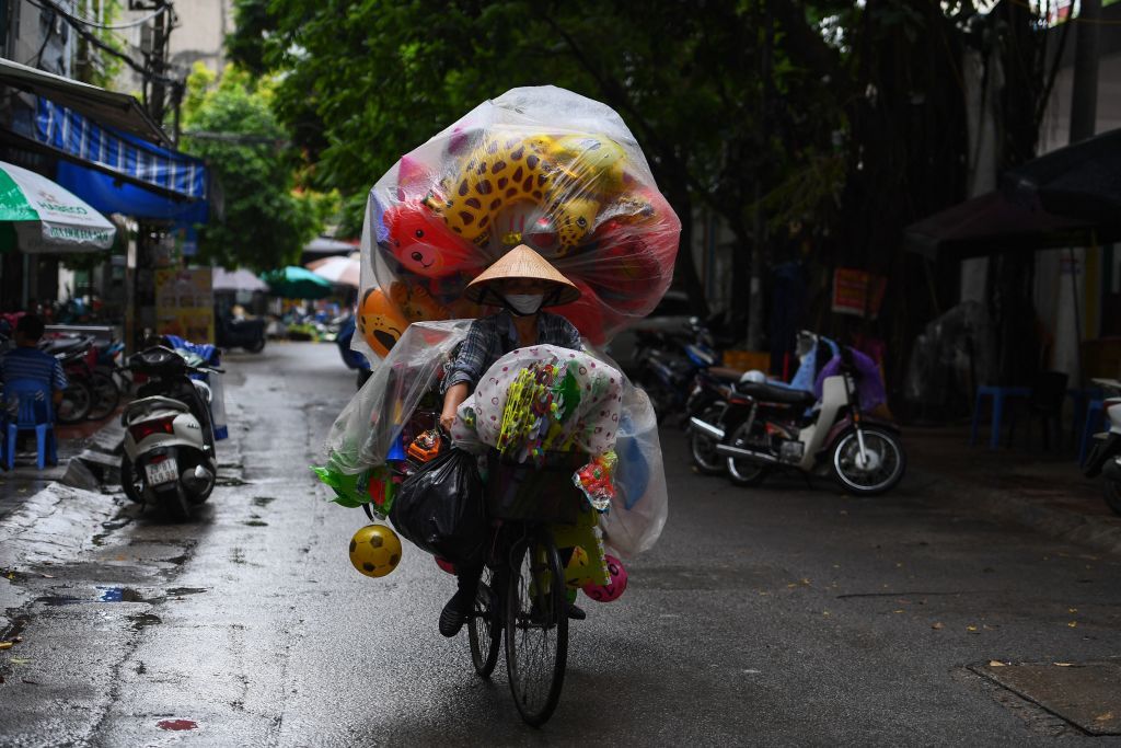 Торговец на велосипеде с товаром, защищенным от дождя