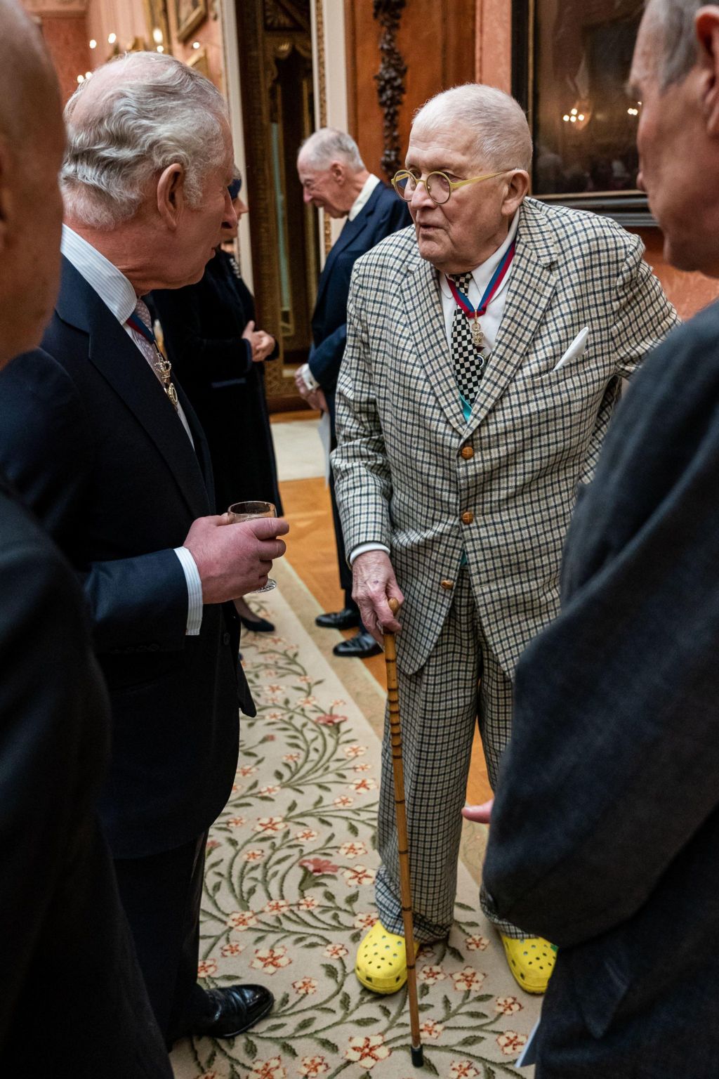 Charles and Hockney speaking, with Hockney in bright yellow Crocs