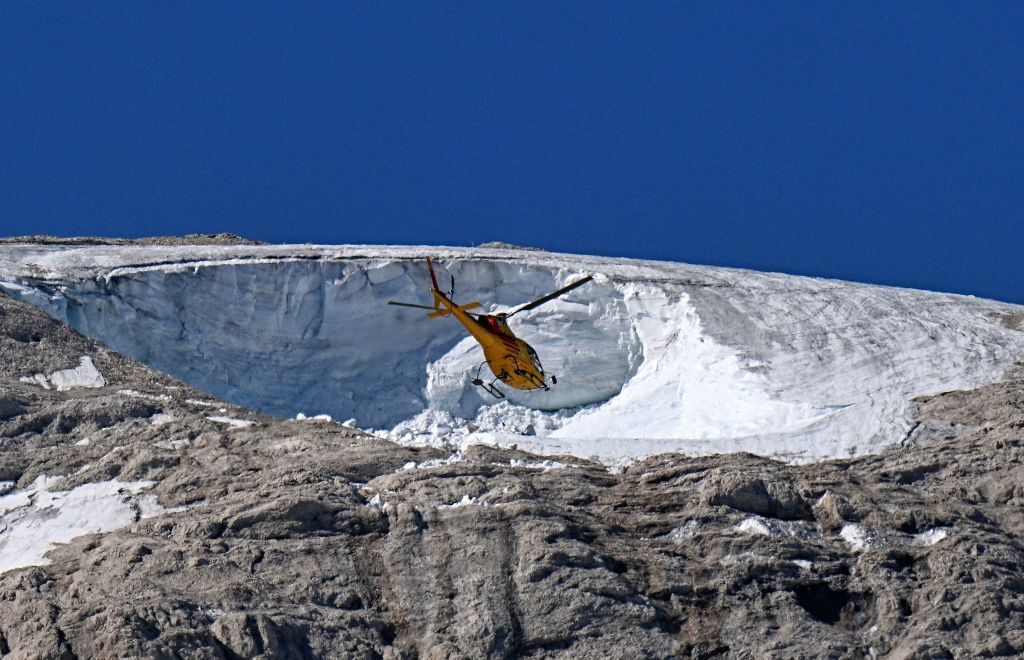 A rescue helicopter flies over Italy's Punto Rocca glacier, in July 2022