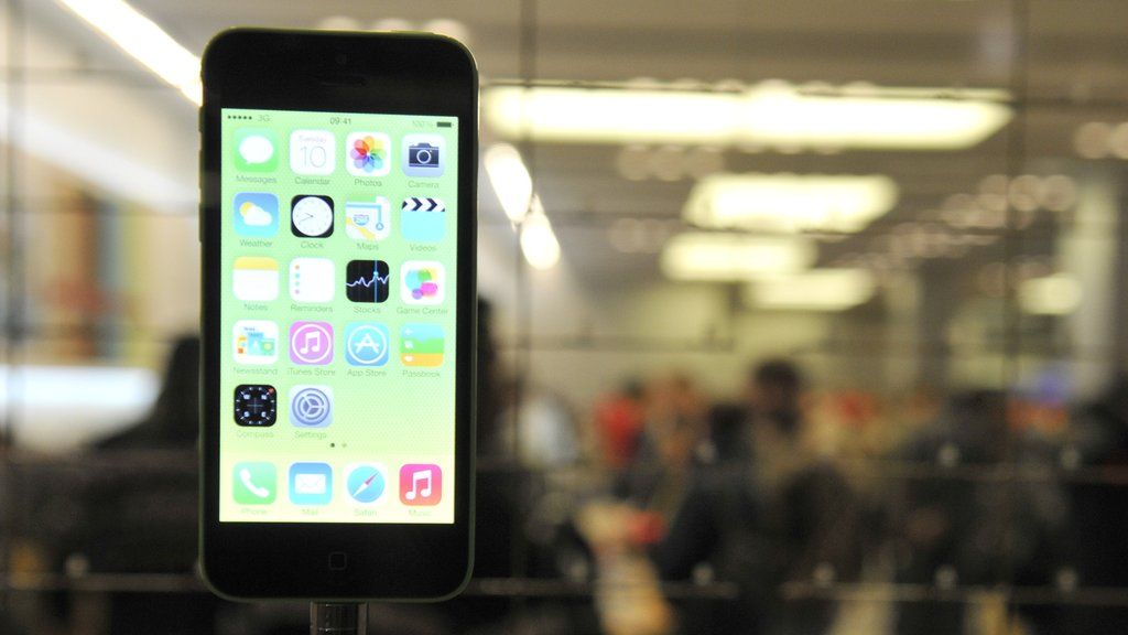 An iPhone 5 is shown in an Apple store windown display