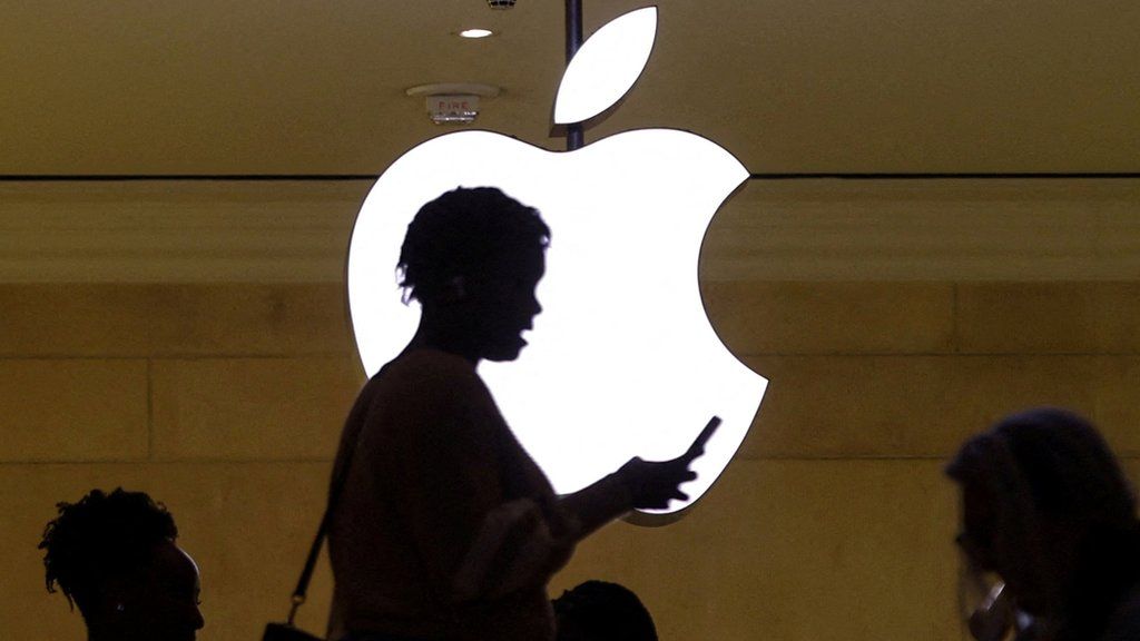 a photograph of a woman checking her phone in front of an Apple logo