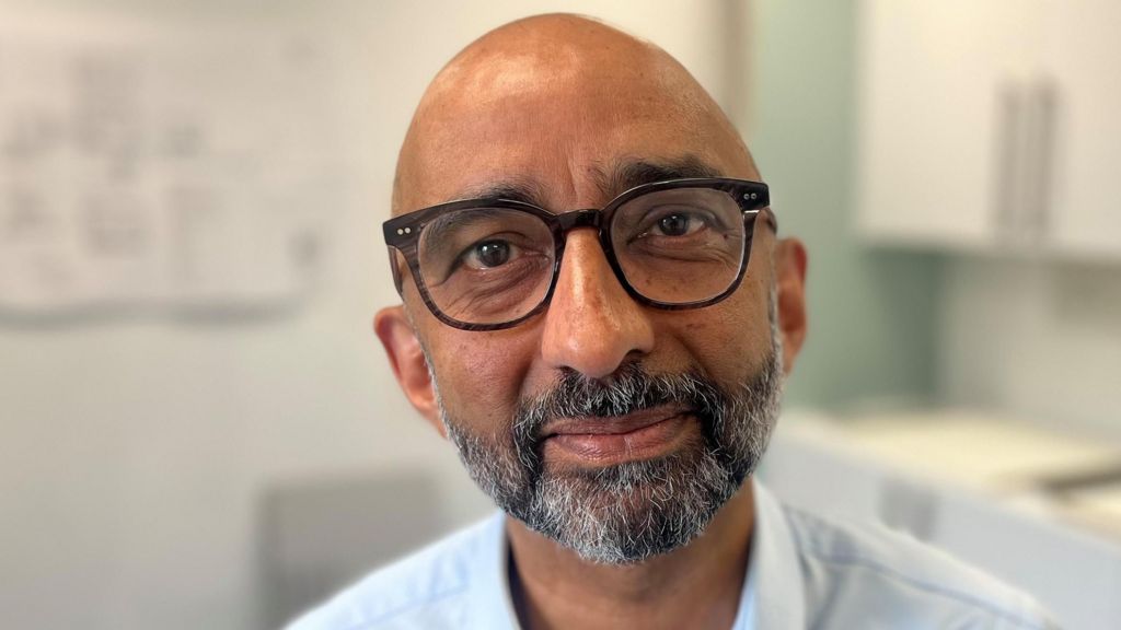 Dr Saket Priyardarshi looking directly at the camera. He has a beard and is wearing glasses.