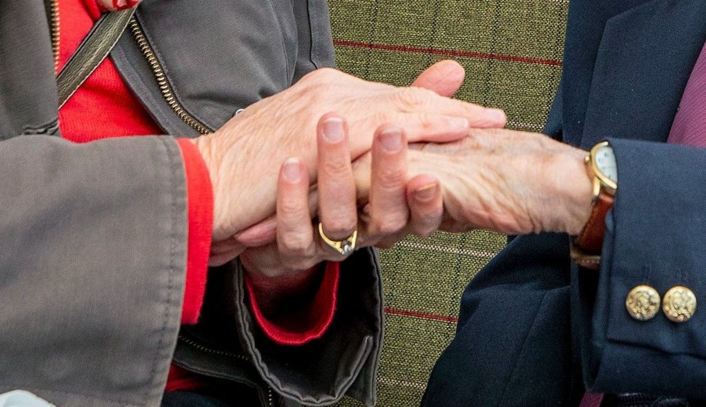 Older person's hand between clasped between a younger person's hands