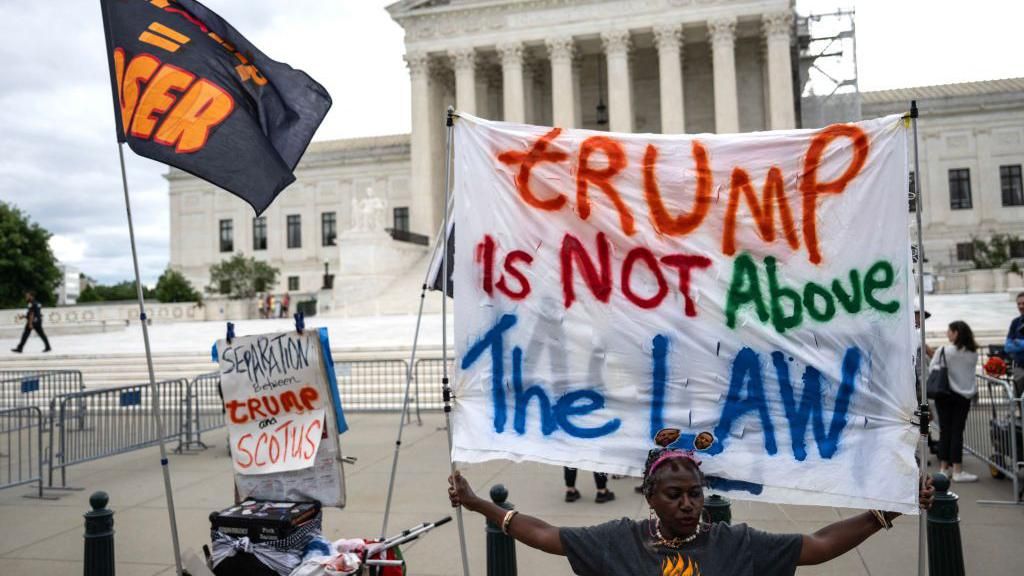 Woman holding sign that "Trump is not above the law" outside Supreme Court