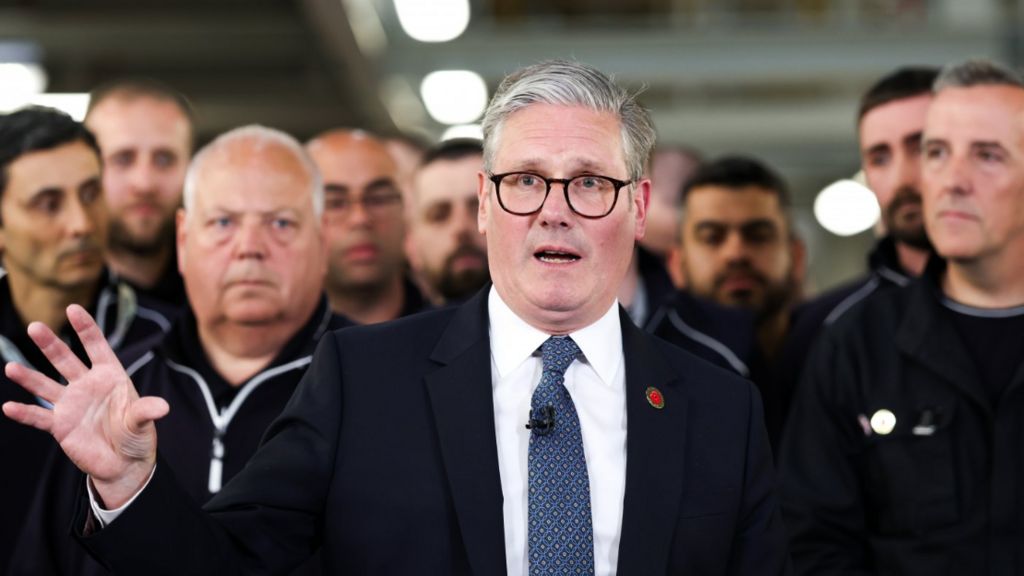 UK Prime Minister Keir Starmer (centre) speaks to the media after a phone conversation with US President Donald Trump, at a Jaguar Land Rover automobile manufacturing plant in the West Midlands back in May. JLR workers are crowded behind him.