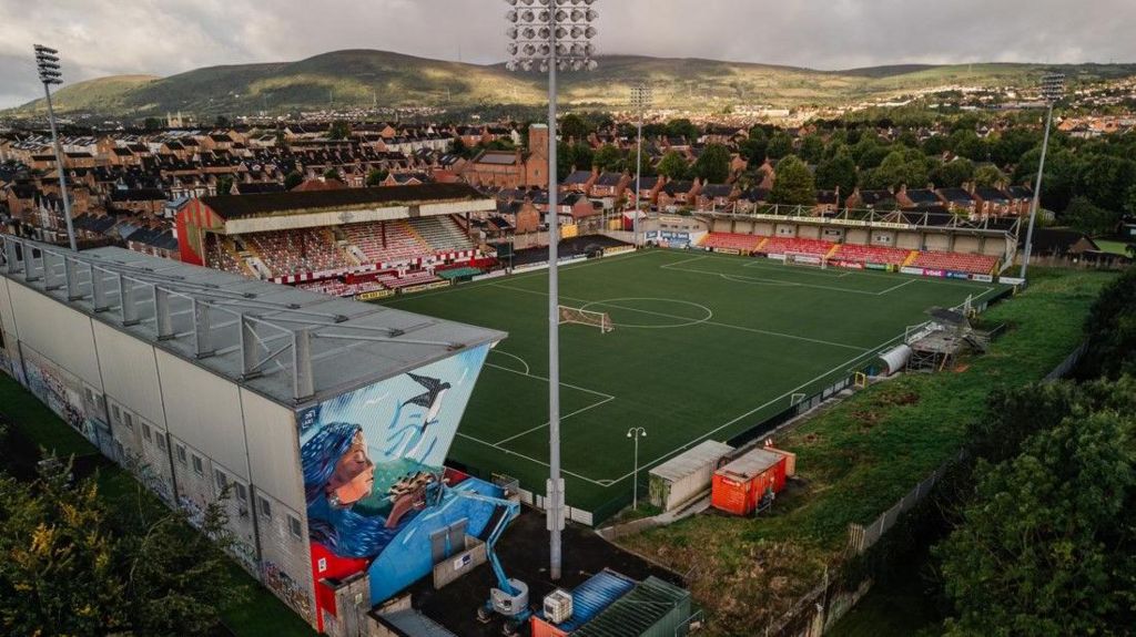 A mural on the side of a stand with a football stadium in the background