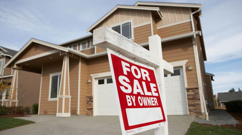 A house in Washington with a red for sale sign in its front garden. 