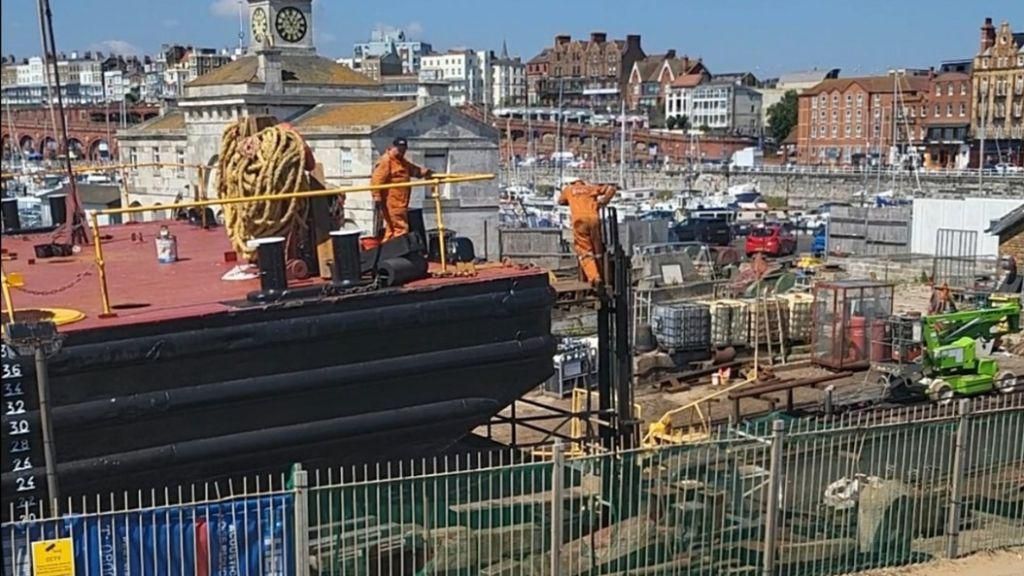 Worker using a pallet raised by a forklift truck at Ramsgate Harbour