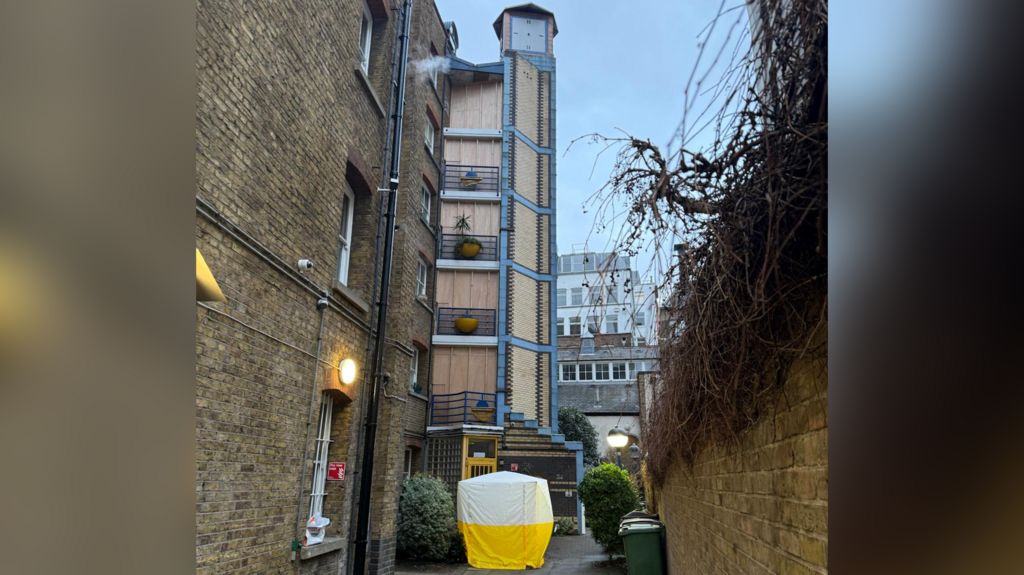 The building is shown with boarded up areas and a police investigation tent on the ground floor