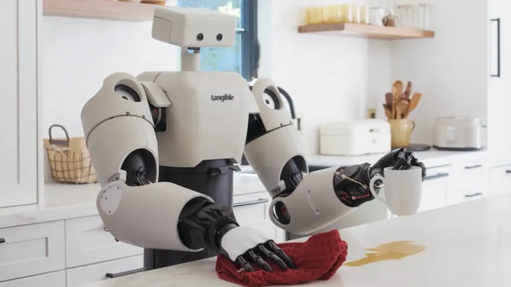 Eggie the robot from Tangible AI clearing up a spill on a kitchen counter. Eggie is about 4.5ft tall and egg shell covered with bulky robotic arms and a head like a shoe box.