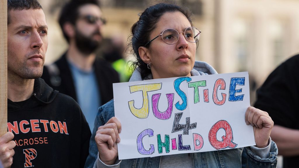 A protester holds a placard saying 'justice 4 child Q' with other activists in shot, outside BBC Broadcasting House in London in March 2022