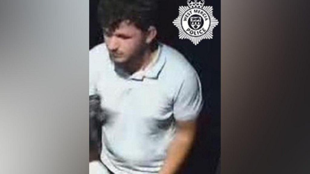 CCTV screenshot image of man wearing white T-shirt and dark grey jeans