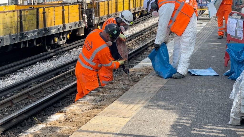 Men in hiviz are removing slabs from a platform