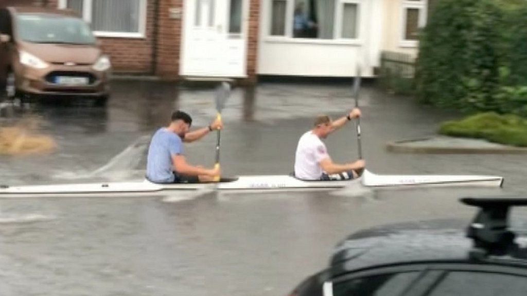 Kayakers paddle down a flooded street