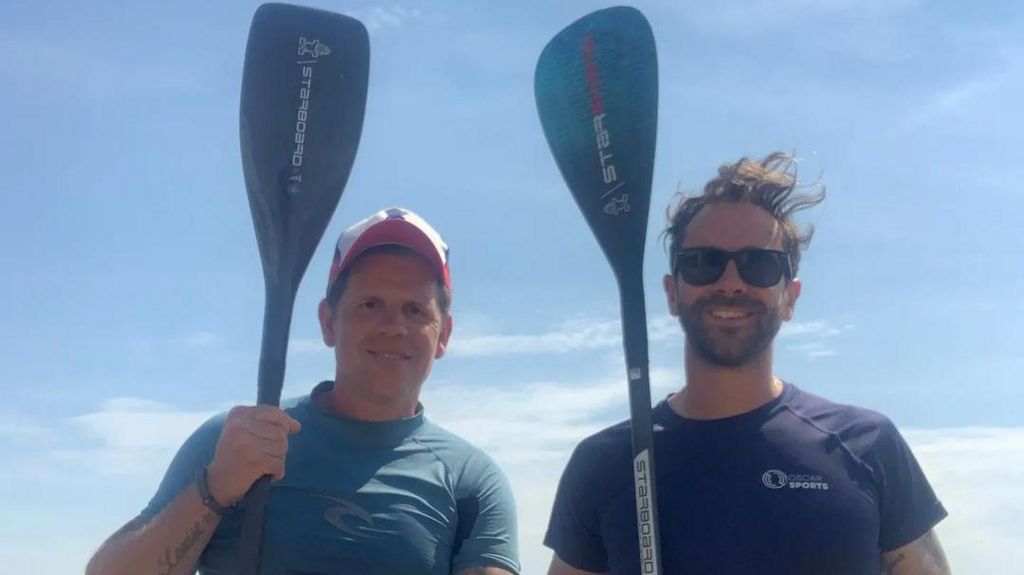 Joe Cartright and David Haze holding up two paddleboards