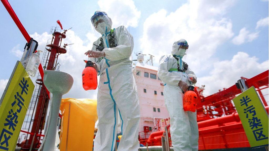 Police officers wearing protective gear against the spread of Covid-19 spray disinfectant at Nanjing port in China's eastern Jiangsu province on 4 August 2021.