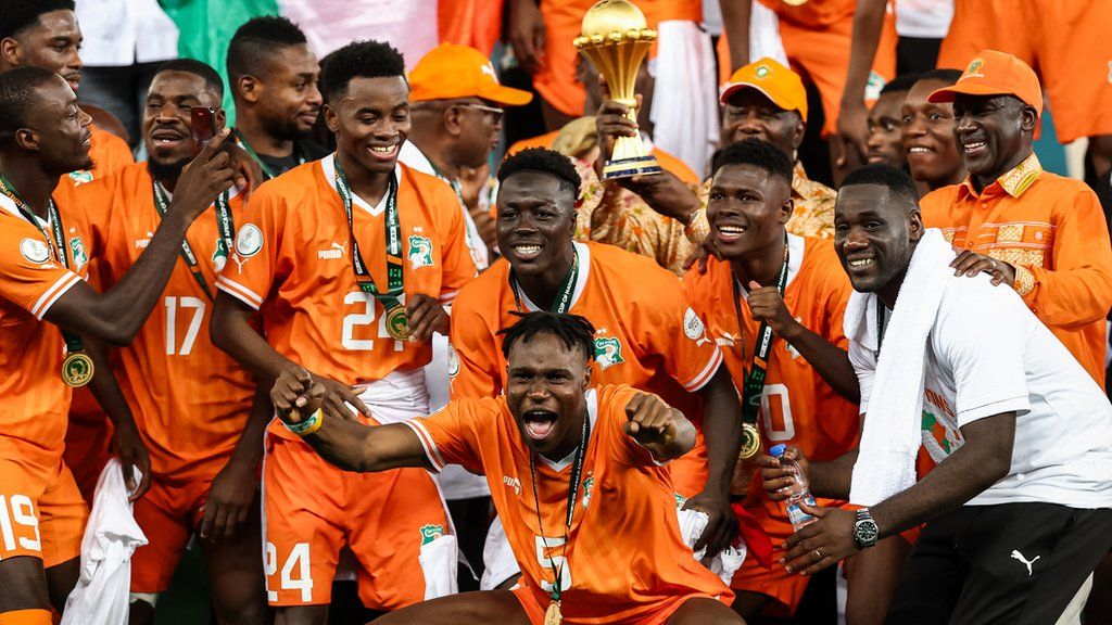 Emerse Fae (far right) celebrates winning the 2023 Africa Cup of Nations trophy with Ivory Coast