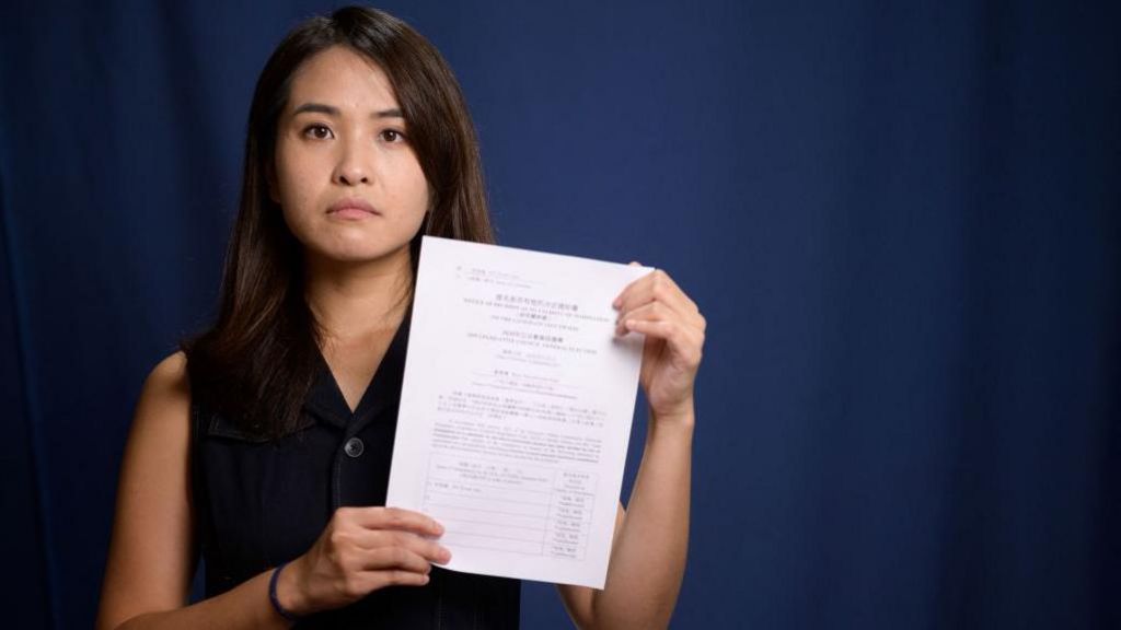 In this picture taken on August 4, 2020, pro-democracy activist Gwyneth Ho, who was recently banned from standing in upcoming local elections, poses with her disqualification notice at her office in Hong Kong