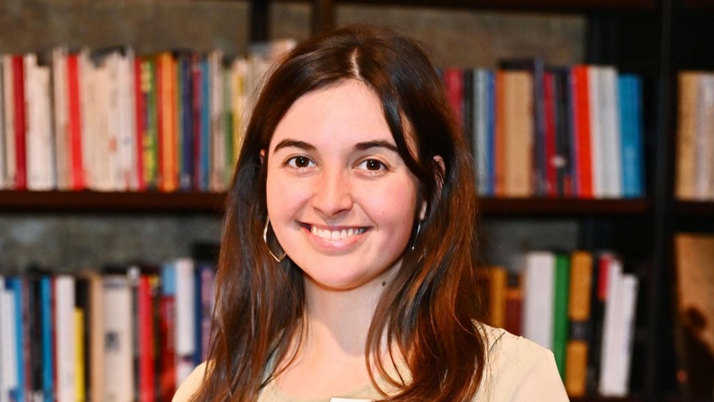 Ava Pickett head and shoulders shot; she has long brown hair and is wearing silver hooped earrings.