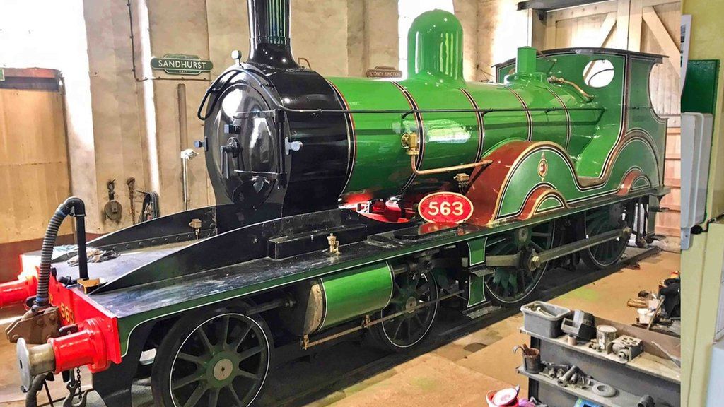 Green and black steam locomotive in a workshop