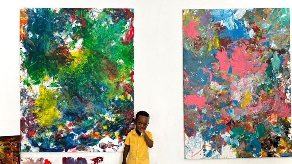 A toddler standing in front of abstract paintings