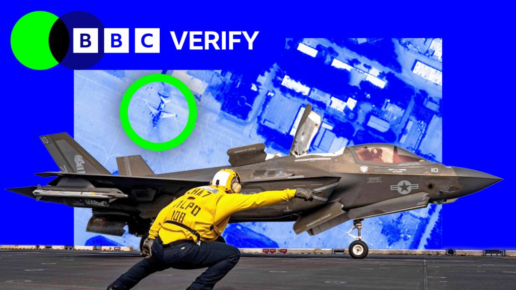 A US navy airman gives an F-35 fighter a signal to take off. He is wearing a yellow jacket and a helmet and is pointing towards the runway. The jet is armed with missiles and is painted grey. The image is imposed over a satellite photo of an airbase in Iran where damaged jets are highlighted.