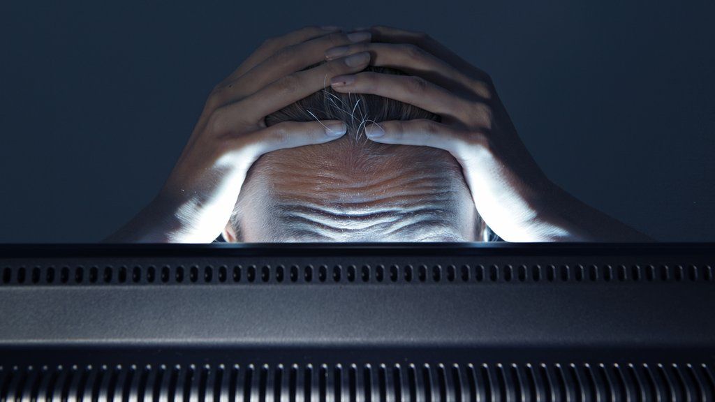A stock image of a person staring in frustration at a computer monitor