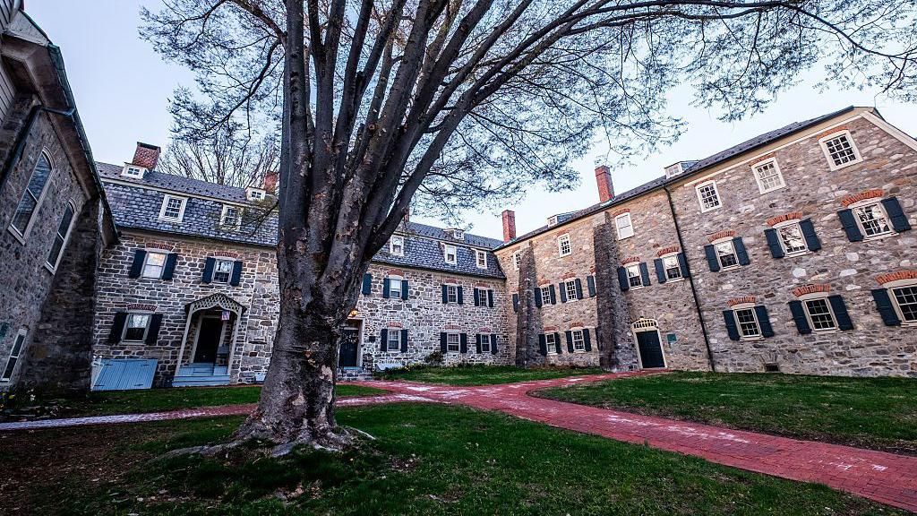 A large old brick building surrounds a green court yard