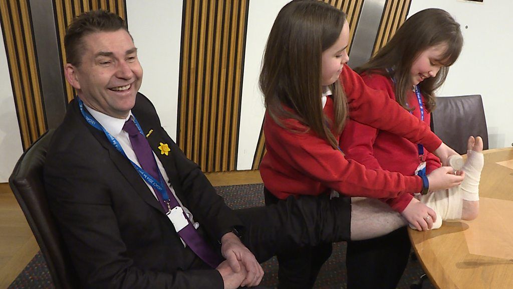 Two primary school pupils demonstrate first aid skills to MSP Brian Whittle