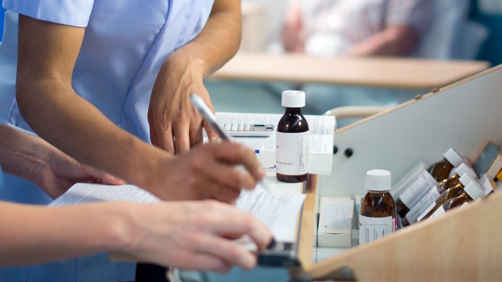Nurses writing next to medicine bottles