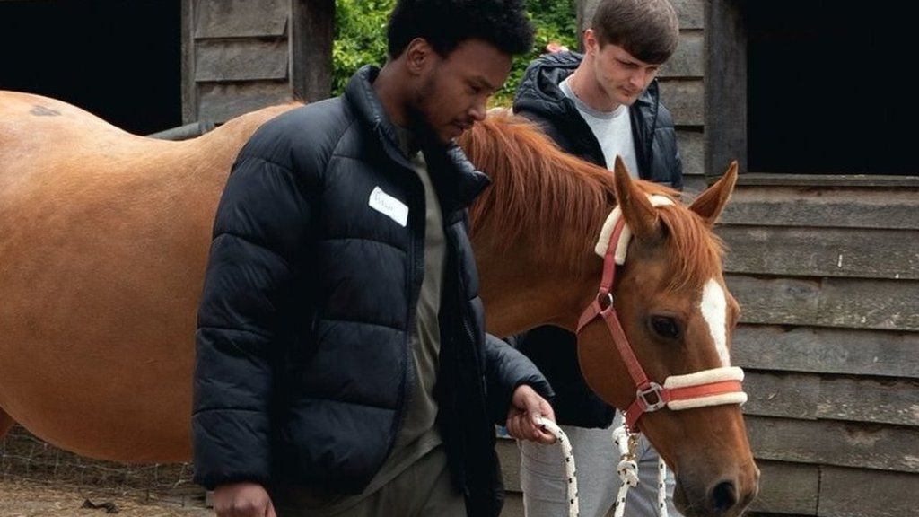 Two young men lead a horses