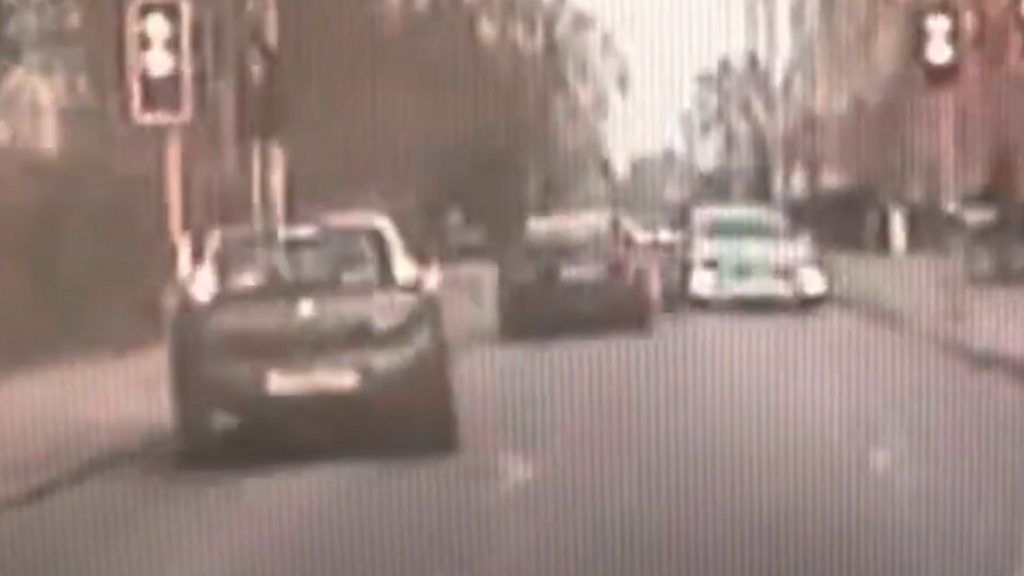 Police dashcam shows a driver narrowly avoiding other cars and bikes while trying to evade officers.
