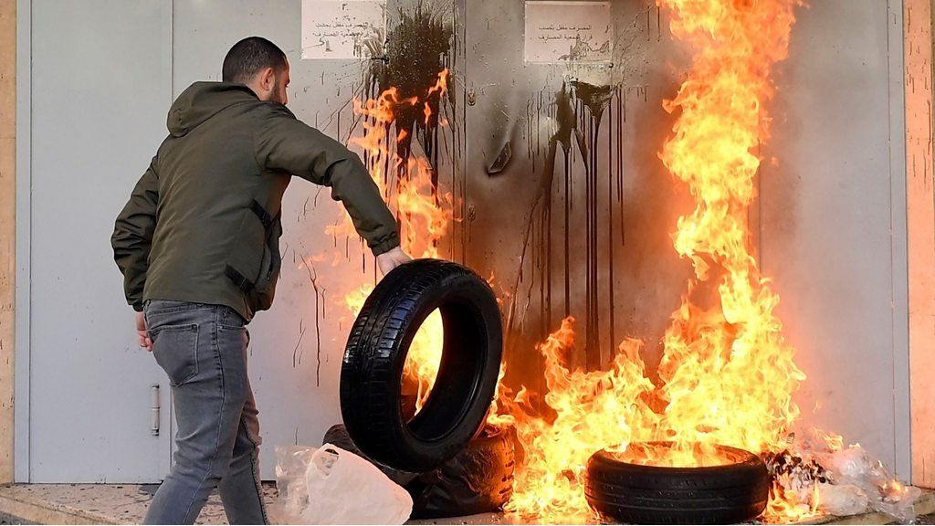 A man rolling a flaming tyre