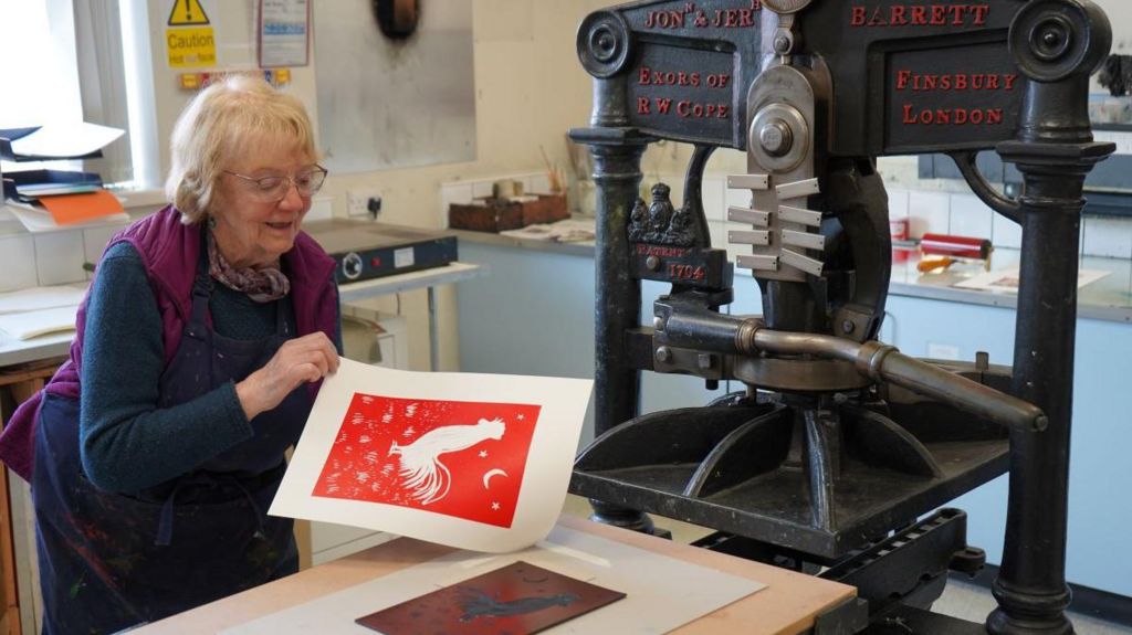 Ms Monaghan is pictured with the finished product of her pressing, which is a red and white print of a cockerel