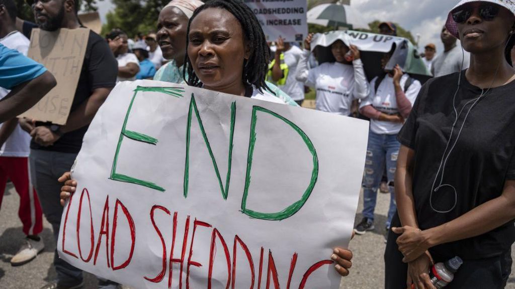 People, holding banners, stage a protest against energy crisis after electricity outages for long periods of time in Johannesburg, South Africa on February 02, 2023