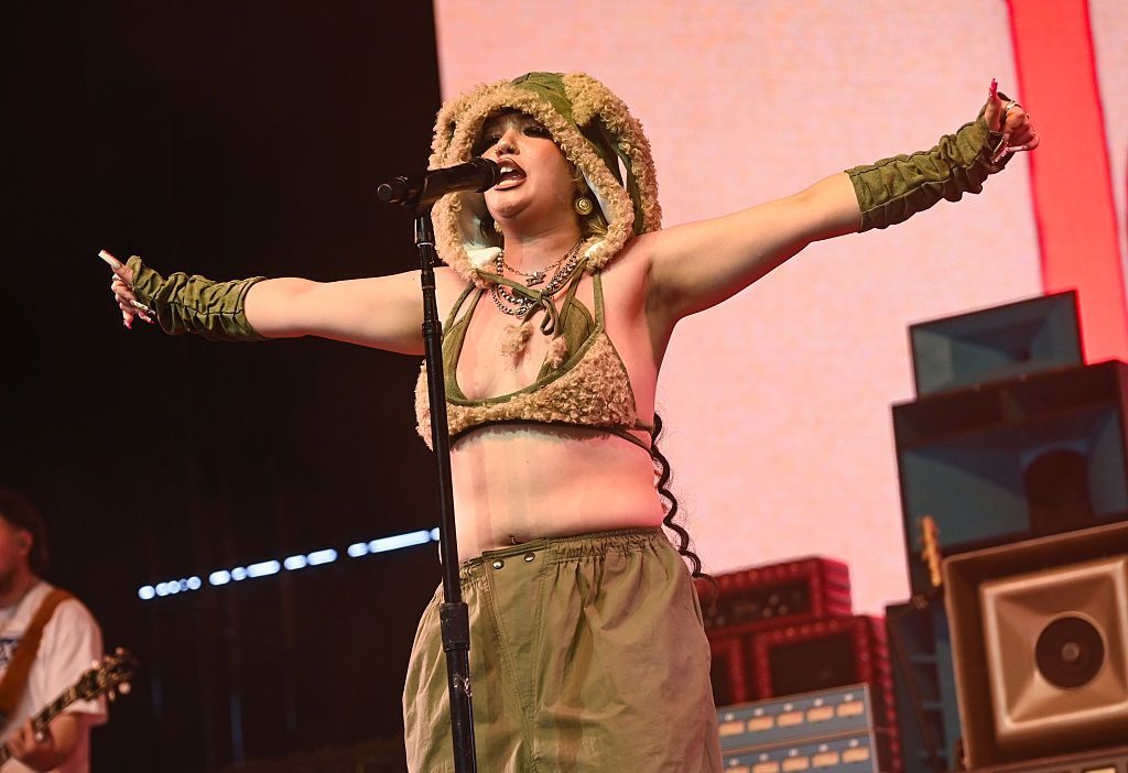 Lola Young holds her arms outstretched, while performing at the Coachella Festival