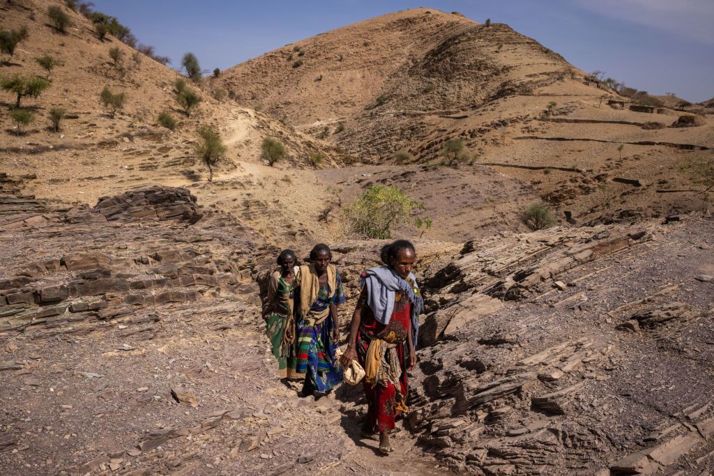 Women walk through a rocky landscape in Tigray