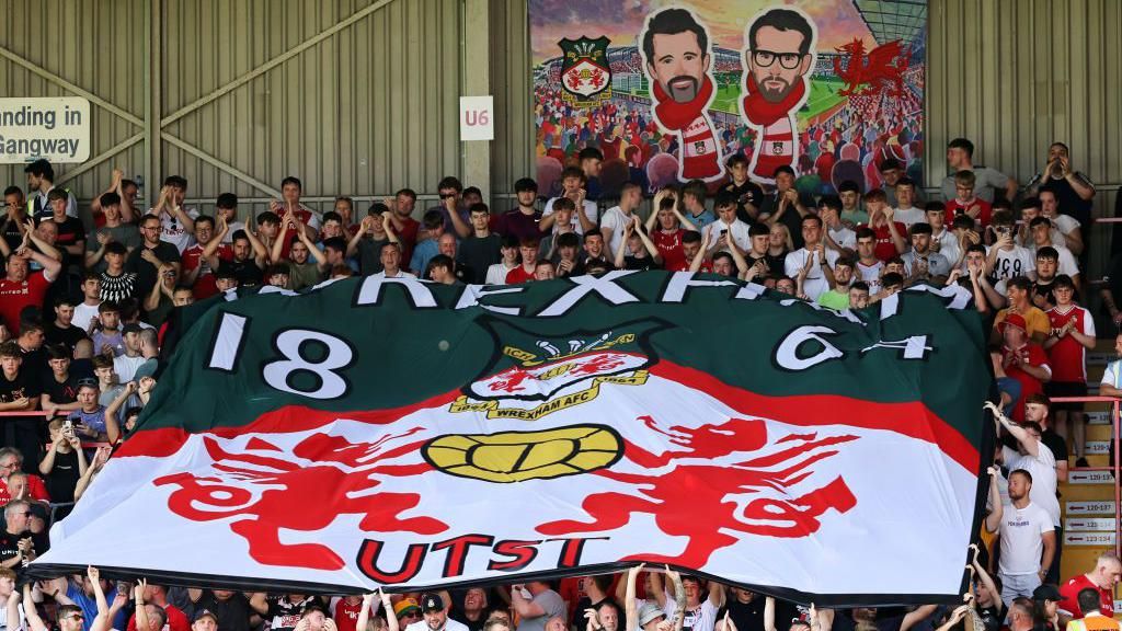 Flag with the faces of Rob McElhenney and Ryan Reynolds on it at Wrexham