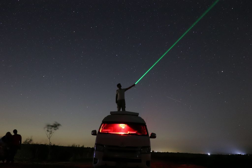 A person is playing with a laser while watching the galaxy and stars in Faiyum, Egypt, on 13 August.