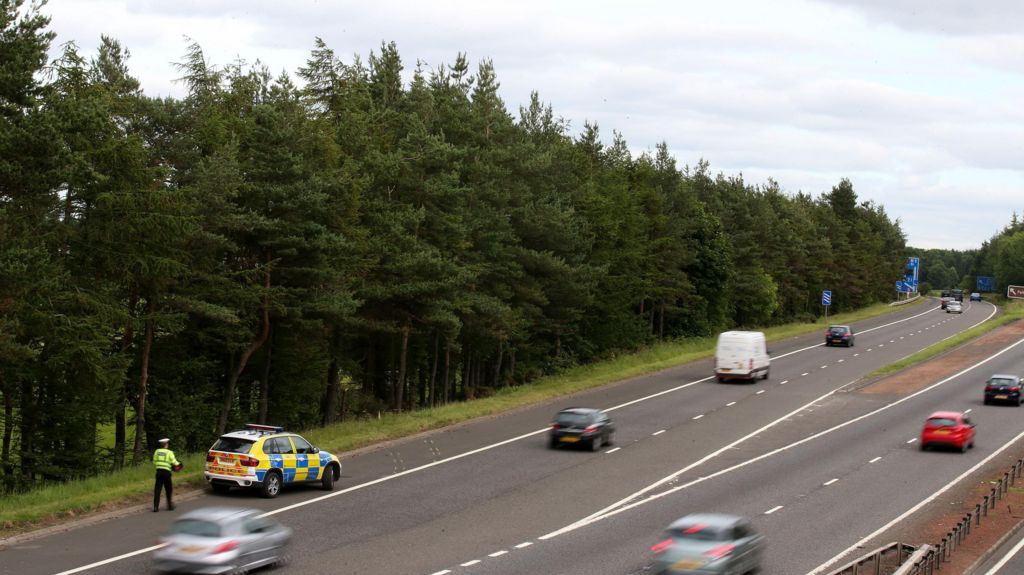 A police car sits near to Junction 9 of the M9 after a car was discovered