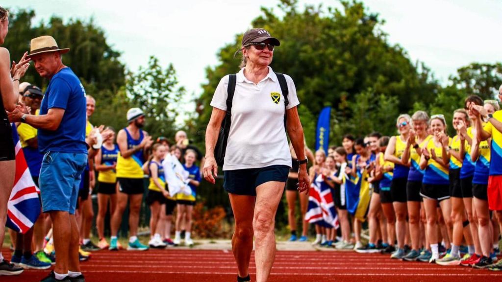 Deborah Steer walks down the track being clapped by crowds.