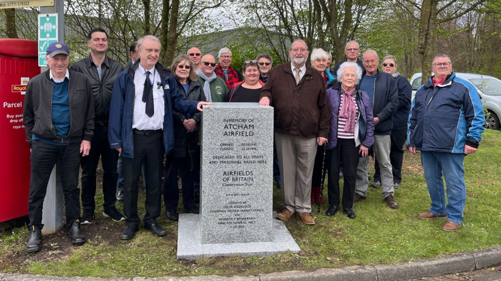 People standing next to a memorial stone